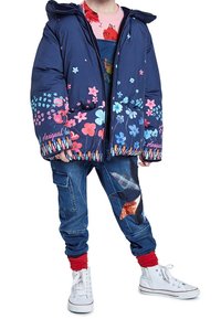 Námořnická bunda s kapucí a květinovými vzory v růžové a modré, se zipovým uzávěrem. V kombinaci s džíny s přízvukem červené barvy a příložkami.