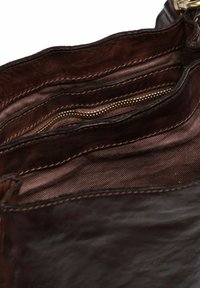Bovenkant van een bruine leren handtas met meerdere compartimenten, waaronder ritszakken. Soepele textuur en rijke kleur met subtiele stikdetails.