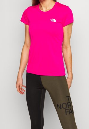Femme portant un t-shirt rose vif à manches courtes et un legging bicolore noir et olive avec des logos The North Face.