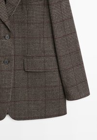 Blazer a quadri marrone con tessuto testurizzato, chiusura frontale a due bottoni, revers a punta e una tasca sul petto con un sottile motivo a pied-de-poule.