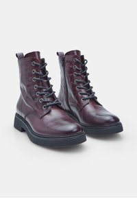 Stivali alla caviglia in pelle bordeaux con finitura liscia, puntale laccato, cerniera laterale e suola nera spessa. Design a punta tondeggiante.