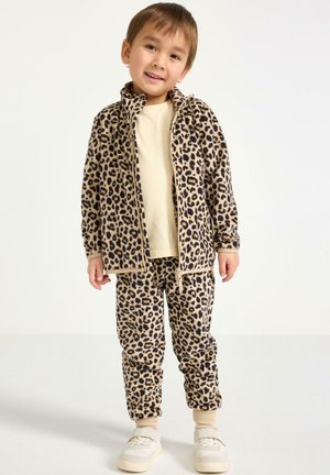 Fleecejakkesæt med leopardmønster i beige og brun, med lynlås foran og snoretræk i taljen. Hvide sko.