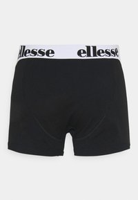 Svarta bomullskalsonger med vit elastisk midja som har "ellesse"-logotypen i svart. Slät textur och åtsittande design.