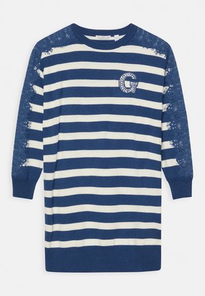 Robe pull rayée avec des rayures bleu marine et blanches, manches accentuées de dentelle et logo "G" incrusté de strass sur la poitrine.