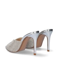 Mules plateados de tacón abierto con un upper metálico texturizado y un elegante tacón de aguja alto, con una plantilla marrón y un acento en el tacón transparente.