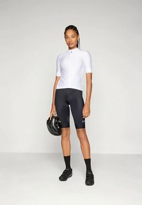 Balts īsām piedurknēm velosipēdu krekls ar vertikālu ribotu tekstūru, apvienots ar melniem velosipēdu šortiem. Turētājs ar melnu ķiverni, melnām zālēm un zeķēm.