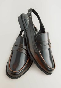 Scarpe slingback in pelle nera con finitura liscia, dotate di una cintura decorativa e sottili accenti marroni, su un tacco basso.