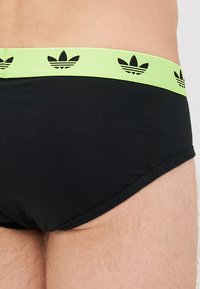 Fekete alsónadrág kontrasztos neon zöld derékrésszel, fekete Adidas logóval díszítve. Simogatóan sima, rugalmas anyagból készült.