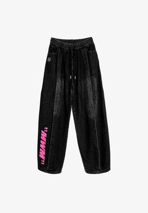 Joggers de mezclilla negra con cintura elástica, cordón, rayas laterales y texto gráfico rosa en la pierna izquierda. Corte holgado, tejido texturizado.