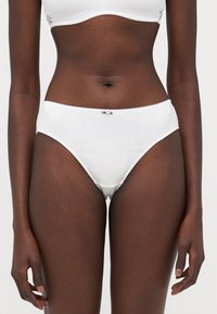 Witte katoenen slips met een gestructureerd patroon, elastische tailleband en een klein roze strikje in het midden vooraan. Mid-rise snit en een gladde afwerking.