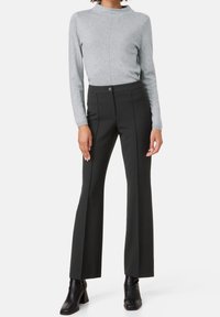 Šedý dlouhý rukáv top spárovaný s černými flared kalhotami s vysokým pasem. Kalhoty mají přední kapsy a zapínání na knoflík. Boty jsou z černé kůže.