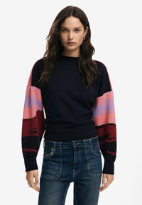 Sweatshirt blu navy con maniche lunghe a fantasia nei toni di rosa, rosso e viola; colletto e orlo a costine; tessuto morbido e vestibilità rilassata.