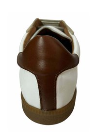 White leather shoe with a brown leather heel cap, textured rubber sole, and contrasting stitching. Features a rounded shape and back pull tab.