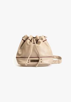 Sac seau en cuir beige avec fermeture à cordon, accents bordeaux, détails en rivets et panneau de base texturé. Bandoulière ajustable incluse.