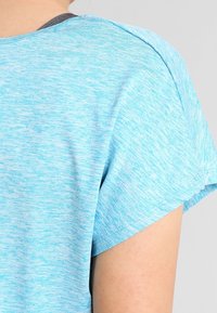 T-shirt de color azul claro con textura jaspeada, mangas cortas y escote redondeado. Material de algodón con un acabado suave. Detalle de costura visible.
