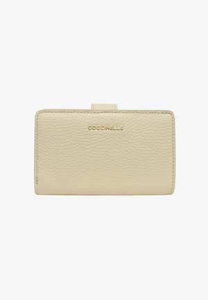 Portafoglio beige in pelle lavorata con bordi cuciti e chiusura a linguetta, caratterizzato dal logo "COCCINELLE" in lettere dorate al centro della parte anteriore.