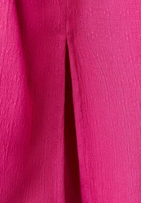 Tissu texturé rose vif avec une fente verticale centrale créant une ouverture étroite.