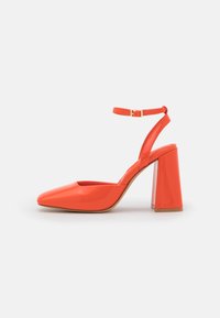 Chaussure slingback en cuir verni orange avec un talon carré épais, un bout pointu et une bride à la cheville. Texture lisse et finition brillante.