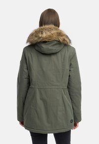 Olivgrön parka-jacka med foder i päls, med insnörjd midja, långa ärmar och sänkt nederkant, visad från baksidan.