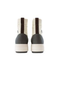 Höga sneakers med ett övre i vitt tyg, grå gummiklack och brun accentremsa. Tjock vit mellansula och texturerad baksida.