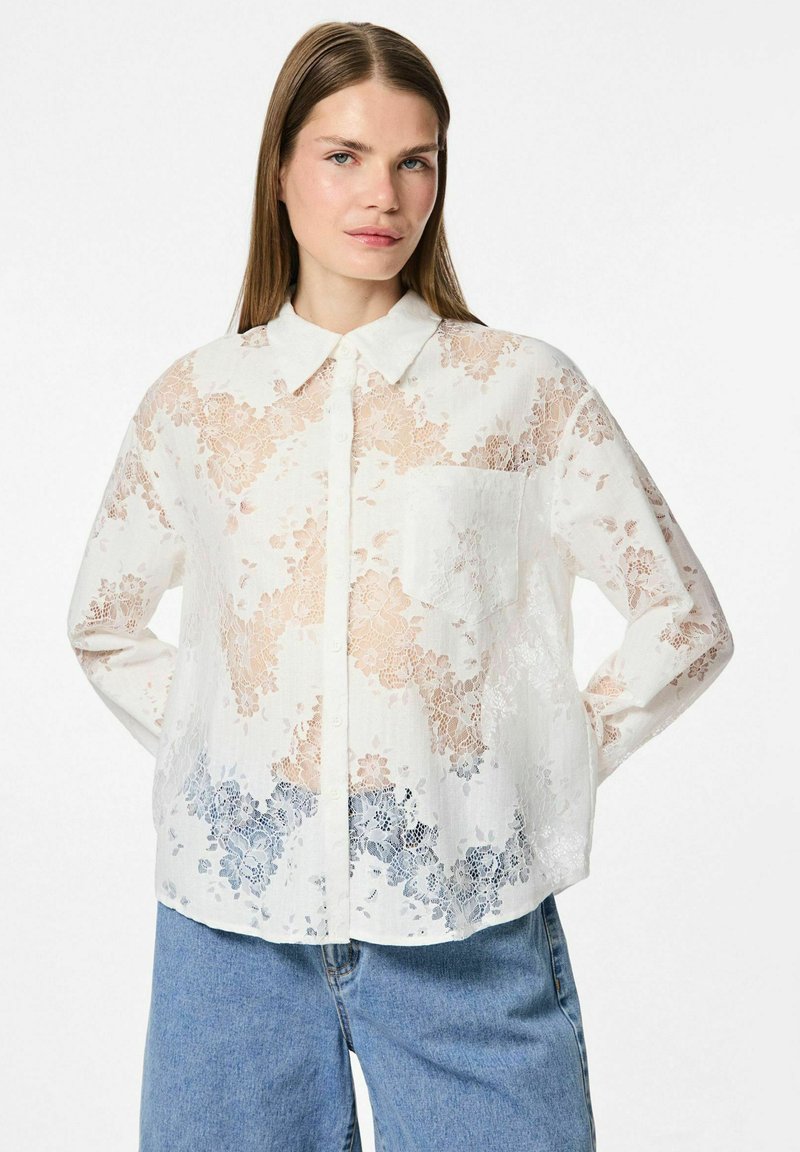 Witte kantblouse met bloemenpatronen in lichte perzik- en blauwe gradaties, voorzien van een kraag, knoopsluiting en een borstzak.