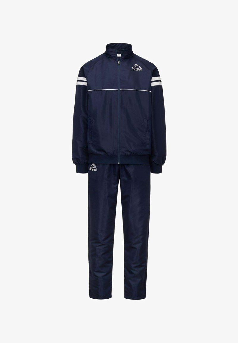 Tuta navy realizzato in un tessuto liscio e lucido; presenta una giacca con zip e strisce bianche e pantaloni coordinati, entrambi con elementi che riportano il logo.