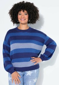 Gestreifter Strickpullover in dunklen und hellen Blautönen mit Rundhalsausschnitt und langen Ärmeln, kombiniert mit hellen Jeans mit Sternmustern.