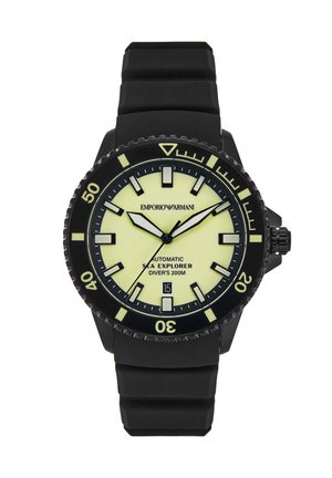 Reloj de buceo automático negro con correa de goma, esfera luminosa amarilla en contraste, bisel negro y display de fecha a las 6 en punto.