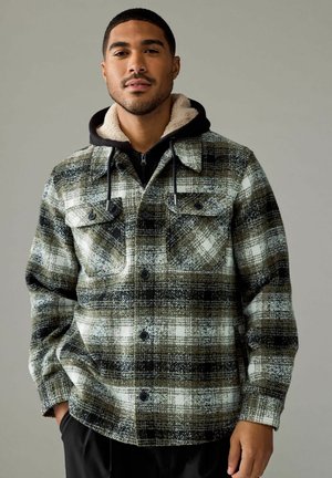 Chaqueta de franela a cuadros en tonos de negro, blanco y verde oliva, con dos bolsillos en el pecho, una capucha forrada de sherpa y un diseño de botones en la parte delantera.