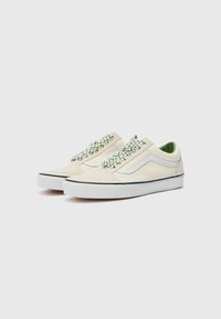 Canvas sneakers in lichtcrème met groen geruite veters, witte accenten en een gestructureerde rubberen zool met een zwarte rand.