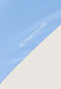 Lichtblauwe stof met een gladde textuur, met de merknaam "TOM TAILOR" in het wit op een hoek, omlijnd met subtiele stiksels.