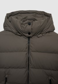 Brown padded jacket with a high collar, featuring a front zipper, snap buttons, and fine horizontal stitching. Soft, smooth texture.