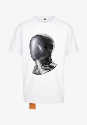 Fehér póló, fekete grafikával, amely egy kapucnis alakot ábrázol. A dizájn tükröződő textúrát tartalmaz a kapucnin és egy kiemelkedő logót.