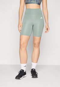 Lysegrøn højtaljede cykelshorts lavet af strækstof, med elastisk talje og kontrasterende hvidt logo på venstre ben.