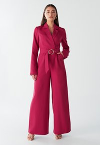 Fuchsia jumpsuit met lange mouwen, een gesneden revers, een ceintuur in de taille en een wijde pijpontwerp. Gladde stofafwerking met minimale details.