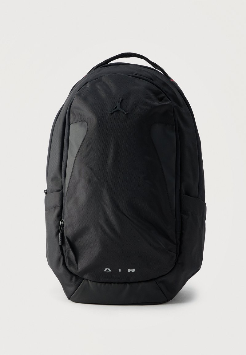 Black backpack with dual front pockets, side compartments, top handle, and small Jumpman logo above reflective "AIR" text.