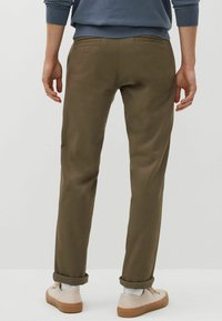 Pantaloni verde oliva con una vestibilità slim, orli arrotolati e due tasche posteriori. Tessuto strutturato con una finitura liscia, abbinati a sneaker chiare.
