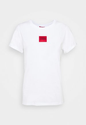 Wit katoenen T-shirt met een ronde hals en korte mouwen. Heeft een rood rechthoekig label met de tekst "HUGO" in witte letters.