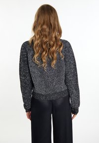 Maglione lavorato a maglia nero e grigio con vestibilità ampia, maniche larghe e orlo a coste, abbinato a pantaloni neri a gamba larga e lisci.