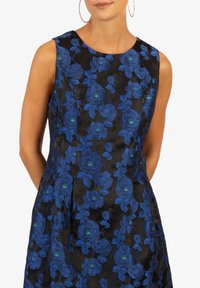Abito nero con un motivo floreale di rose blu e accenti verdi. Design senza maniche con scollatura arrotondata e tessuto strutturato.