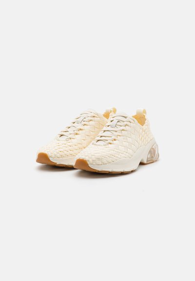 Sneakers intrecciati beige chiaro con parte superiore testurizzata, design con lacci e suola bianca chunky con un accento traslucido.