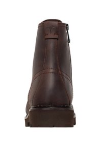 Tmavě hnědá kožená kotníková bota se zadním zipem, poutkem s vyraženým logem a silnou gumovou podrážkou, zobrazená ze zadu.