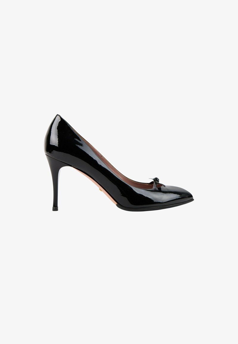 Chaussure à talon haut en cuir verni noir avec bout pointu et petit nœud décoratif sur le dessus, vue de côté sur fond blanc.