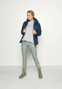 Mornarska puffa jakna, svetlo siva majica, zelene melange leggingse in olivno zeleni gležnjarji. Ima podloženo teksturo in oprijet kroj.