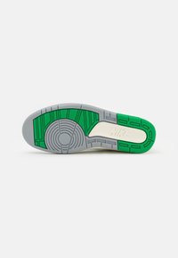 Sole tenisky Nike se šedým základem, s růžovými gumovými akcenty a texturovanými vzory pro trakci. Lehce design s oblíbeným kruhovým detailem.