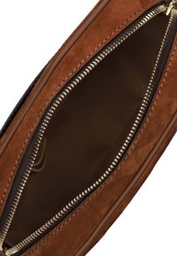 Borsa in suede marrone con apertura a zip, che mostra un interno liscio e scuro e dettagli in cerniera dorata. Il tessuto interno è testurizzato e di colore marrone scuro.
