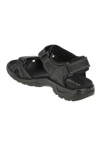 Black sandal with adjustable straps, cushioned footbed, rubber sole, and contrasting light stitching detail, designed for comfort and support.