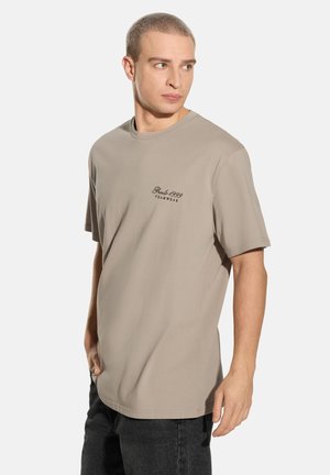 Beżowy bawełniany t-shirt z krótkimi rękawami, okrągłym dekoltem i haftem na piersi w ciemnobrązowym kolorze. Luźny krój i miękka tekstura.