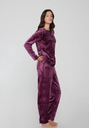 Lila Samt-Lounge-Set mit einem Langarmoberteil und einer Hose mit glatter Textur, Seitentaschen und entspanntem Schnitt.