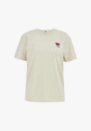 Tricou bej cu mânecă scurtă și guler rotund, cu broderie mică de floare roșie pe partea stângă a pieptului.